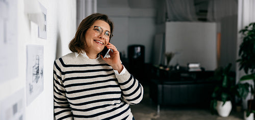 Woman on smartphone in design office speaking with a client in a creative workspace