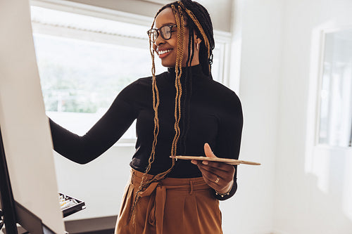 Smiling painter working on a painting in her art studio