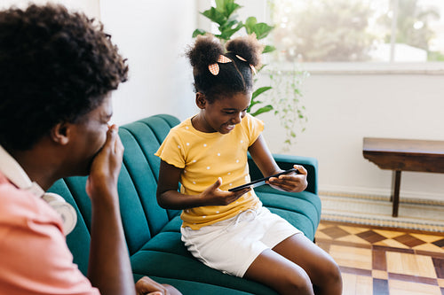 Siblings laughing and watching funny videos on digital tablet at home