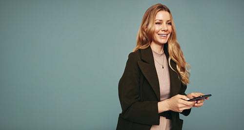 Happy woman holding a mobile phone in a studio