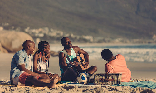 Group of friends having picnic at the seashore