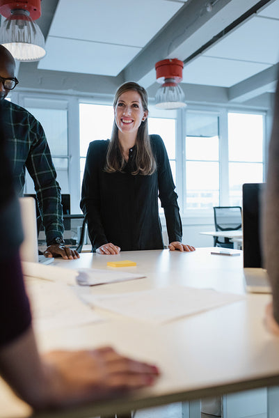 Young woman standing at table with colleagues during a meeting