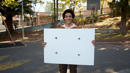 Smiling boy holding a blank billboard outside