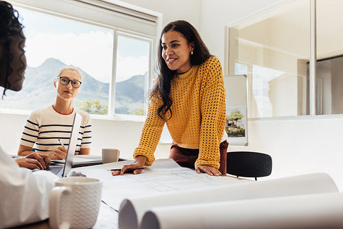 Team of female architects discussing design plans at a professional office workspace.