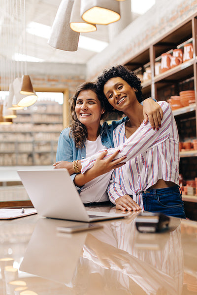 Cheerful ceramic shop owners embracing each other in their store