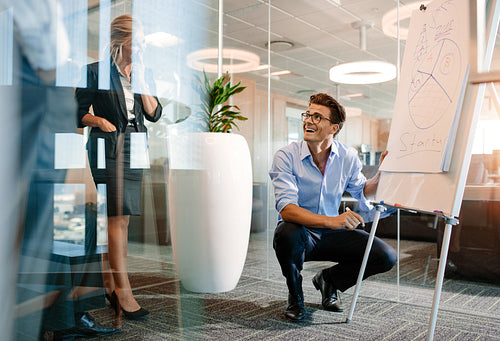Office worker giving a presentation to colleagues and smiling.