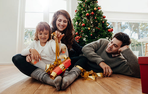 Small family having fun opening Christmas gifts.