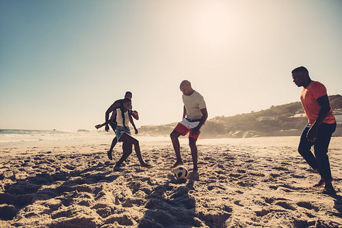 Group of friends playing soccer on the beach