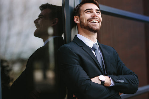 Cheerful businessman standing outside office building