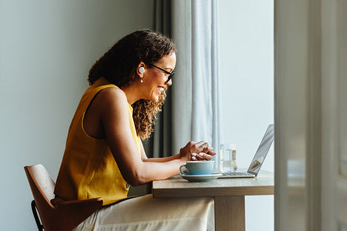 Mixed-race woman video conferencing with laptop in home office