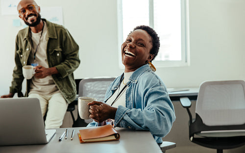 Happy co-workers enjoying a coffee break in a modern office setting