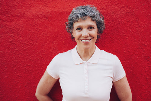 Senior woman standing against red background