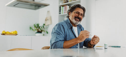 Senior man tests glucose at home with a glucometer