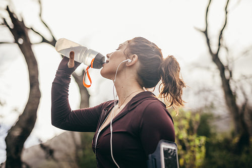 Woman drinking water after a running exercise