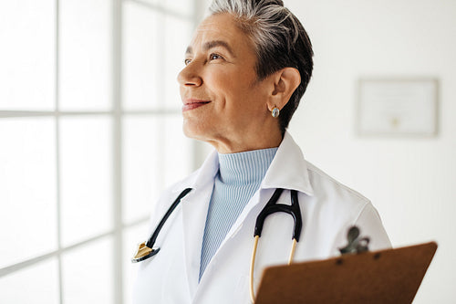 Thoughtful doctor looking outside the window in her office