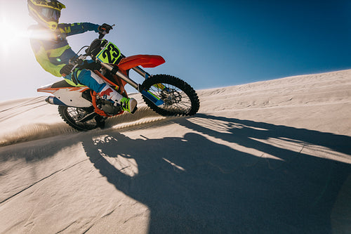Professional motocross biker riding on sand dunes