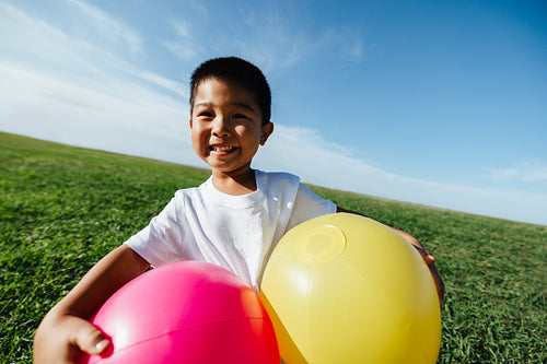Smiling boy with colorful balloons in the park