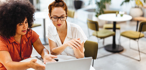 Cafe coworking: Two women discussing work on a laptop
