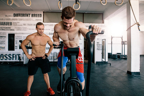 Muscular man spinning on stationary bike in gym