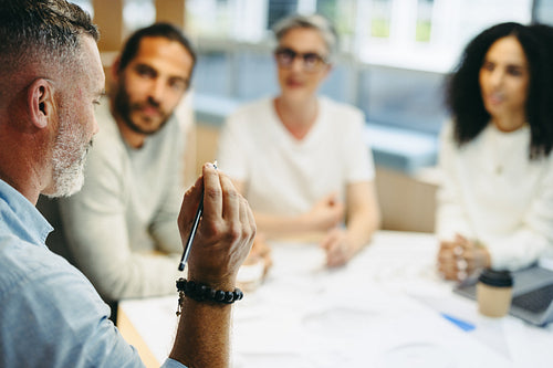 Mature businessman having a discussion with his team in an office