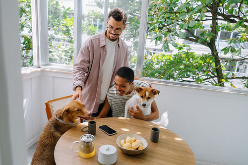 Couple enjoying morning at home with rescue dogs and pão de queijo on table