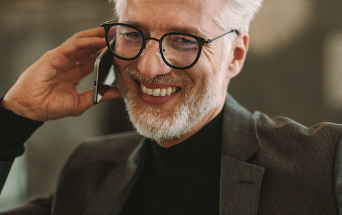 Happy mature businessman talking on phone