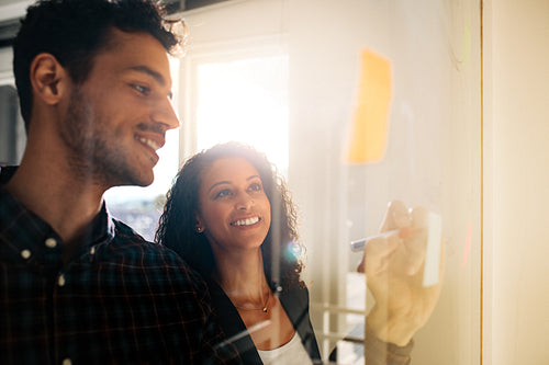 Business colleagues discussing ideas on glass board in office