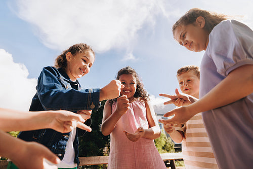 Group of children playing rock-paper-scissors in a park setting