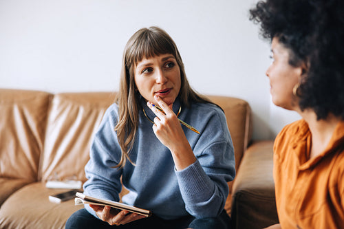 Two young businesswomen having a discussion in an office lobby