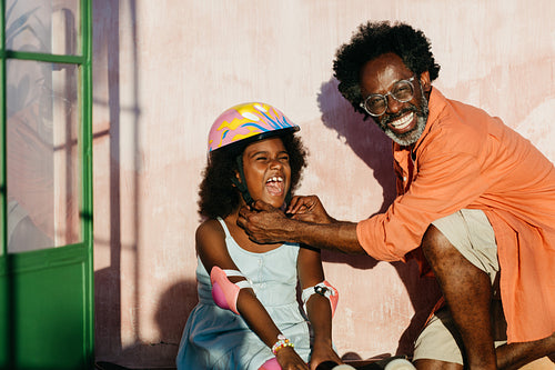 Mature father putting a safety helmet on his daughter for a scootering experience