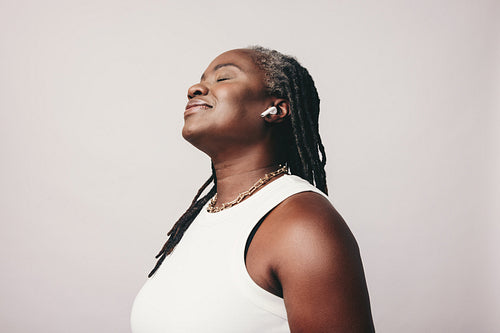 Carefree woman with dreadlocks listening to music in a studio
