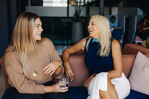 Two women having a friendly conversation in a modern office environment