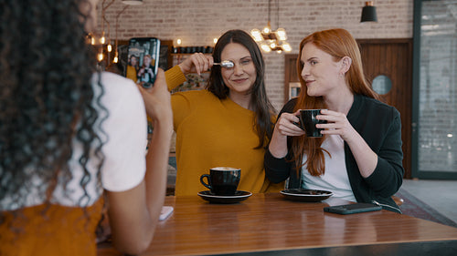Woman taking photos of her friends at a coffee shop