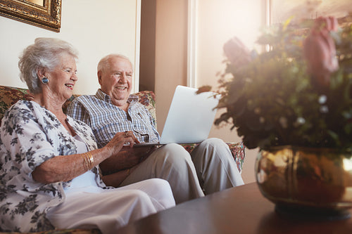 Smiling senior couple using laptop at home