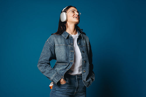 Woman wearing headphones smiling in studio portrait with music and audio technology theme