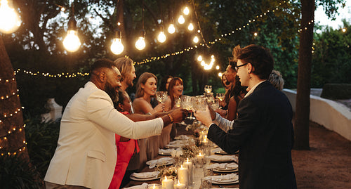 Elegant outdoor wedding dinner celebration with friends under fairy lights