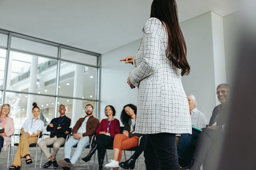 Woman giving a business presentation to a group of colleagues in a modern office setting
