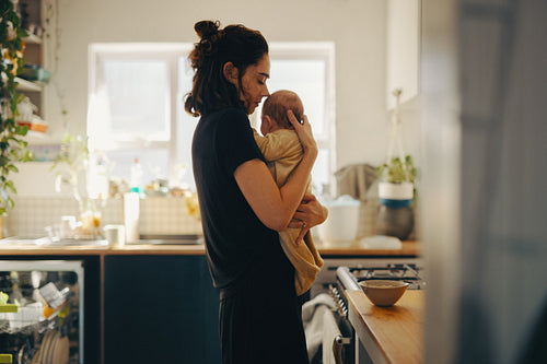 Mother gently embraces her baby in kitchen