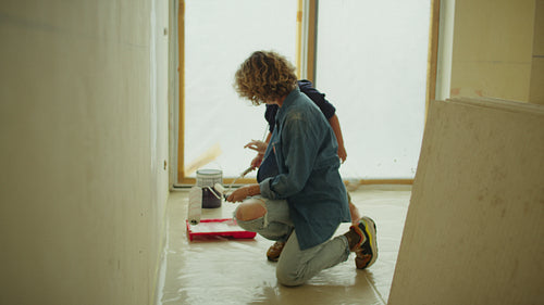 Mother and son painting wall together during home renovations