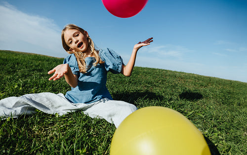 Girl plays with balloons in a grassy field