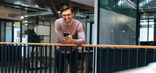 Professional man reading a text message on a smart phone in an office
