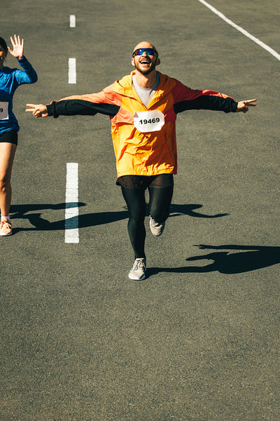 Male runner celebrating victory with arms outstretched on race day