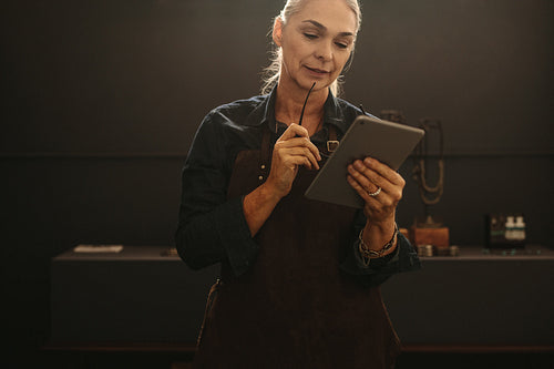 Senior female goldsmith using digital tablet