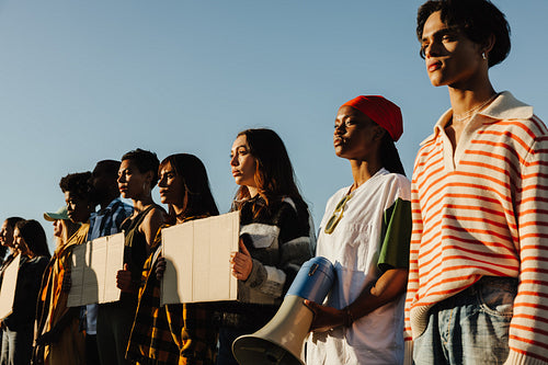Diverse group of individuals standing together in unity under a blue sky