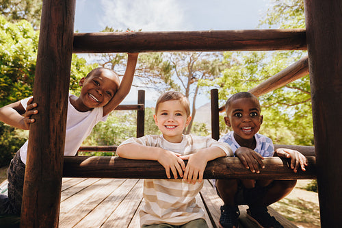 Smiling children playing on a wooden playground outdoors on a sunny day