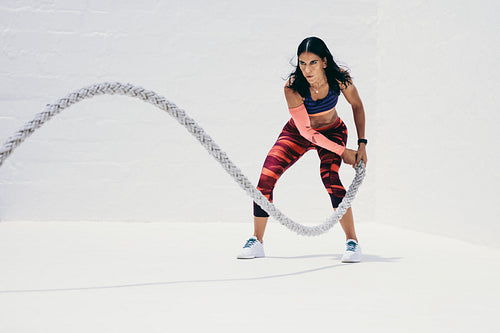 Woman doing fitness workout using battle rope