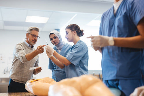 Injection training in medical school: Doctor shows students how to prepare a syringe