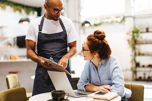 Business woman ordering coffee from a waiter in a cafe