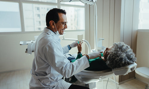 Dentist communicates with senior patient during clinic checkup