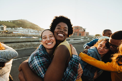 Young adults embracing outdoors with joyful expressions